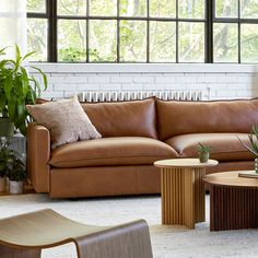 a living room filled with lots of furniture next to a window and potted plants