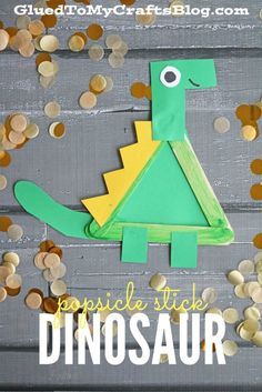 a paper cut out of a green and yellow dinosaur with gold coins scattered around it