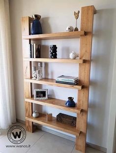 a wooden shelf with books and vases on it in front of a white wall