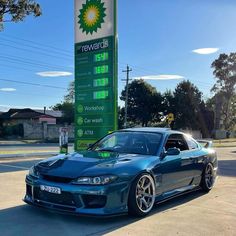 a blue sports car parked in front of a gas station sign