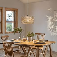 a dining room table with chairs and plates on it, in front of a window