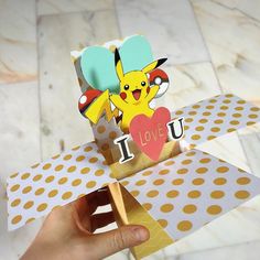 someone is holding up a card that says i love you with a pikachu on it