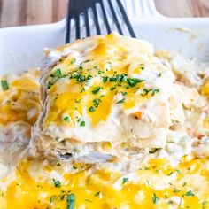 a white plate topped with lasagna covered in cheese and sauce next to a fork