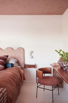 a bed room with a neatly made bed and a chair next to the headboard