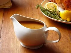 a white pitcher filled with liquid sitting on top of a table next to a plate of food