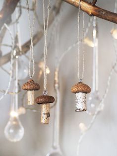 three wine corks hanging from a tree branch with lights in the background and some glass beads attached to them