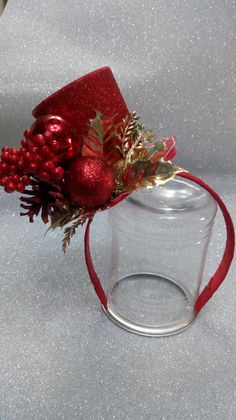 a glass vase with some red ornaments in it and a ribbon around the top, on a table