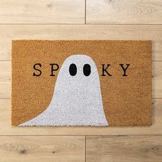 a door mat that says spooky with a ghost face on it in front of a wood floor