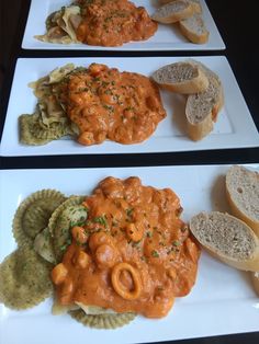 two white plates topped with different types of food next to bread and crackers on a table