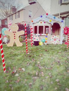 some candy canes and a gingerbread house on the grass in front of a house