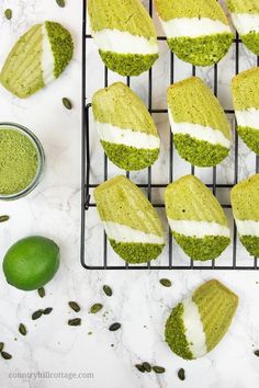 matcha cookies with white and green frosting on a cooling rack next to two limes