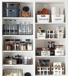 an organized pantry with white shelves and bins