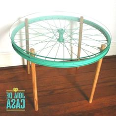 a glass table with wooden legs and a bicycle wheel on it's back end