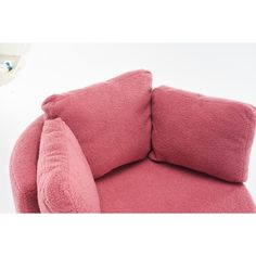 a pink chair with two pillows on it and a white wall in the back ground