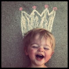 a little boy laying on the ground with a crown drawn on it's head