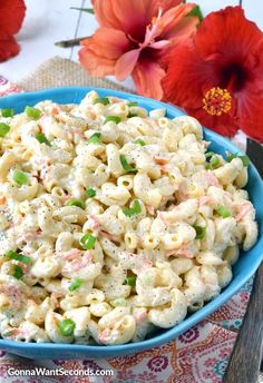 a blue bowl filled with macaroni salad on top of a colorful table cloth