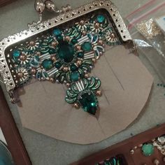 a green and silver purse sitting on top of a table next to other jewelry items