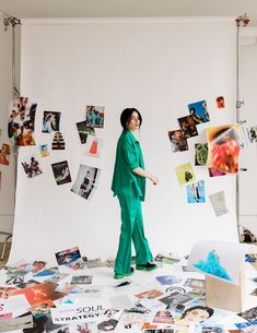 a man standing on top of a table covered in papers and pictures, with one hand up to his head