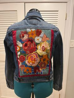 A traditional Levi's denim jacket, size L. Fun and happy self-made embroidery of colorful flowers on the back. Denim Jacket With Multicolor Embroidery And Pockets, Multicolor Embroidered Denim Jacket With Pockets, Cotton Denim Jacket With Floral Embroidery For Fall, Medium Wash Denim Jacket With Floral Embroidery, Floral Embroidered Cotton Denim Jacket For Fall, Medium Wash Cotton Denim Jacket With Floral Embroidery, Floral Embroidered Cotton Denim Jacket In Medium Wash, Fall Cotton Denim Jacket With Floral Embroidery, Fall Floral Embroidered Cotton Denim Jacket