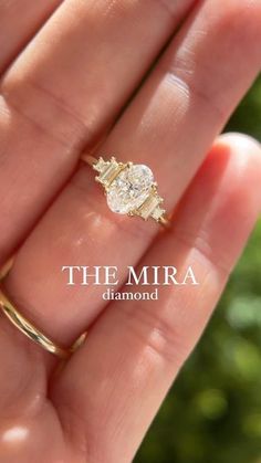 a woman's hand holding an engagement ring in her left hand with the word, the mira diamond on it