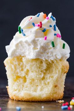 a cupcake with white frosting and sprinkles on it's side