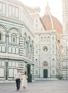 an engaged couple standing in front of the cathedral