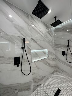 a bathroom with white marble walls and black shower faucets in the shower area