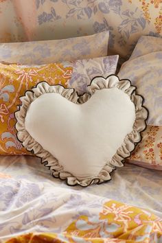 a heart shaped pillow sitting on top of a bed