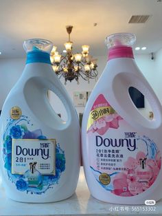 two bottles of downy detergent sitting on a counter in front of a chandelier