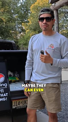 a man standing in front of a truck giving the thumbs up while holding a cell phone