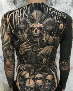 the back of a man with tattoos on his body and two skulls in front of him