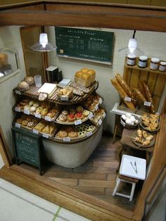 a display case filled with lots of different types of breads and pastries in front of a chalkboard