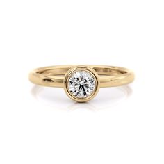 a yellow gold engagement ring with a round diamond in the center, on a white background