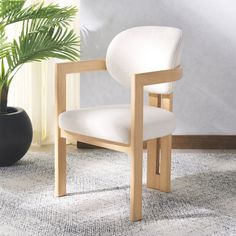 a white chair sitting on top of a rug next to a potted plant