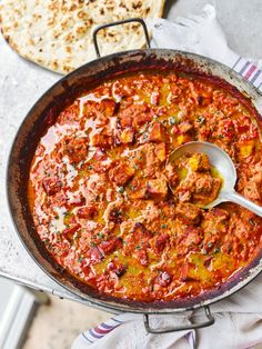 a pan filled with meat and sauce next to some pita bread