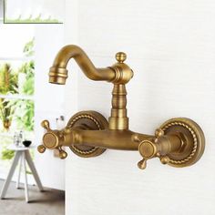 an antique brass faucet on the wall in a room with white walls and windows