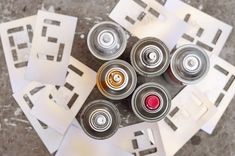 several cans of soda sitting on top of each other next to cut out pieces of paper