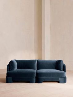 a blue couch sitting on top of a hard wood floor next to a white wall