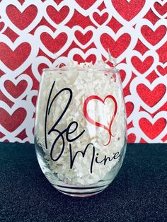 a glass with rice in it and the words be mine written on it next to a red heart wall