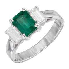 Peter Suchy three-stone emerald and diamond engagement ring. Emerald center stone with two emerald cut side diamonds in a platinum setting created by the Peter Suchy Work Shop. GIA certified. 1 octagon cut green emerald MI, approx. 1.11cts GIA Certificate # 220416561 2 emerald cut diamonds F VS, approx. .60cts Size 6 and sizable Platinum Stamped: PLAT 6.6 grams Width at top: 7.6mm Height at top: 6.1mm Width at bottom: 3.0mm 1950s Engagement Ring, Emerald And Diamond Engagement Ring, Engagement Ring Emerald, Gia Certificate, Contemporary Engagement Rings, Emerald Cut Diamond Ring, Platinum Diamond Engagement Rings, Platinum Diamond Rings, Modern Engagement Rings