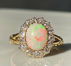 an opal and diamond ring is shown on a white surface, with the light shining through it