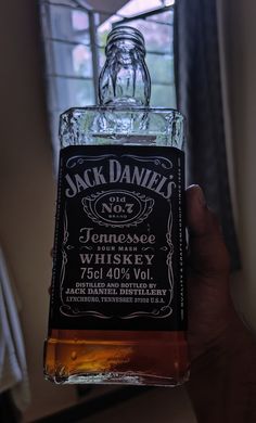 a person holding up a bottle of jack daniels whiskey