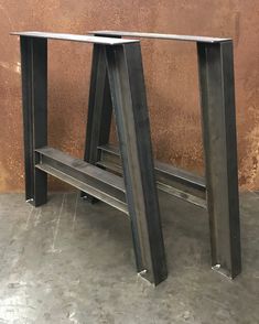 two metal benches sitting next to each other on cement floored area with wall in background