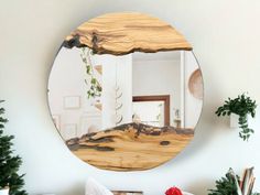 a round mirror hanging on the wall above a table with christmas decorations and other items