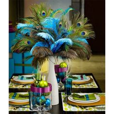 the table is decorated with peacock feathers and other decorations for an elegant dinner or party