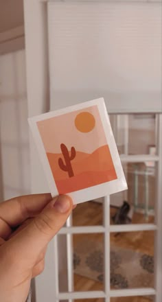 a person holding up a card with an image of a cactus in the desert on it