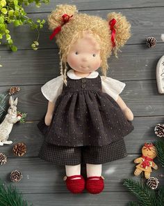 a doll with blonde hair wearing a black dress and red shoes next to christmas decorations