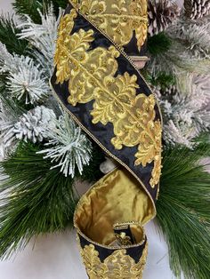 a gold and black christmas ornament hanging from a tree