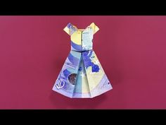 an origami dress made out of money on a purple background with pink backdrop