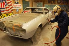 a man is working on a car in a garage with an american flag painted on the wall